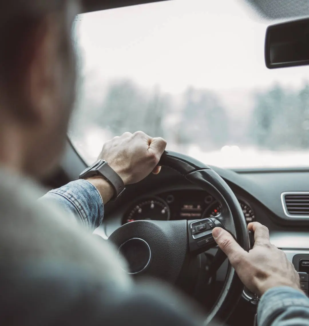 Driver's hands on steering wheel, car interior