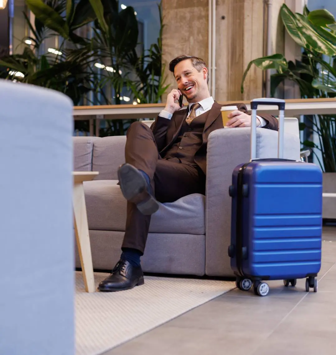 Business traveler smiling on phone with suitcase