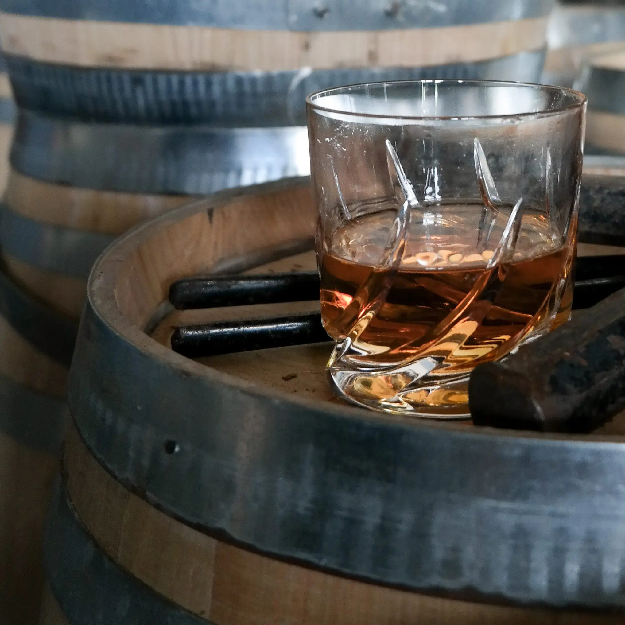 Whiskey glass on oak barrel in distillery