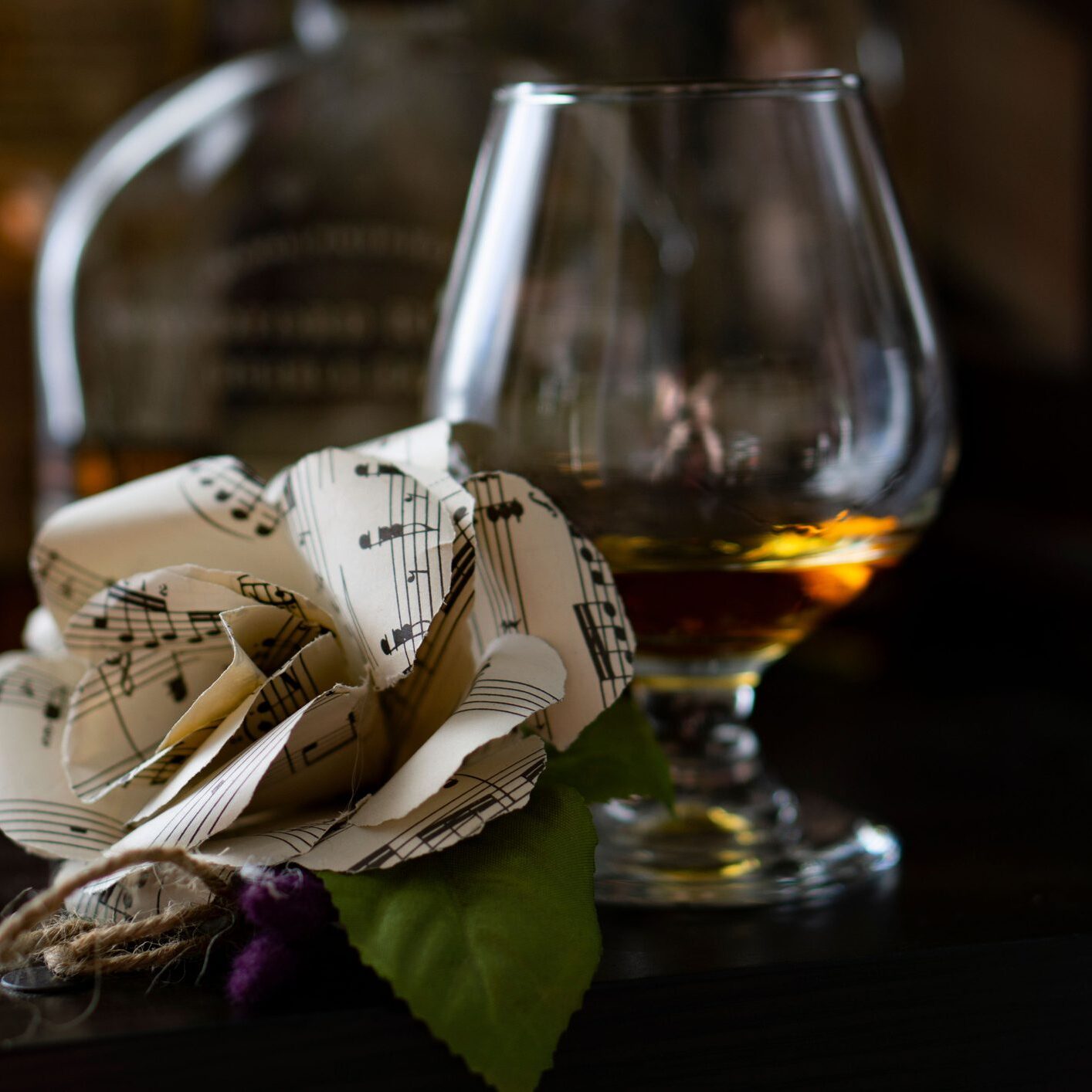 Sheet music paper rose beside brandy snifter